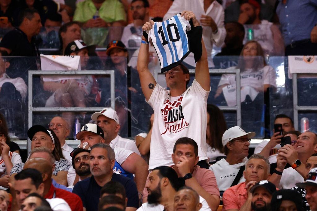 Seorang penggemar klub bola basket Miami Heat mengacungkan jersei tim nasional sepak bola Argentina bernomor 10 milik Lionel Messi pada laga ketiga final NBA antara Heat dan Denver Nuggets di Kaseya Center, Miami, Rabu (7/6/2023). 