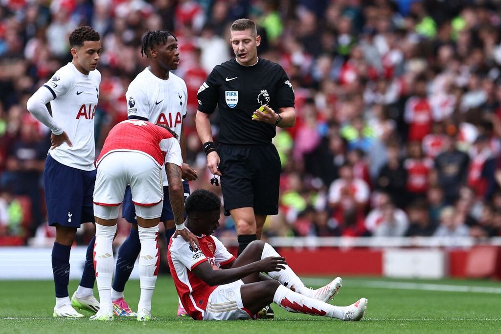 Pemain sayap Arsenal, Bukayo Saka, terduduk setelah ditekel oleh bek Tottenham Hotspur, Destiny Udogie (ketiga kiri), pada laga Liga Inggris, 24 September 2024.