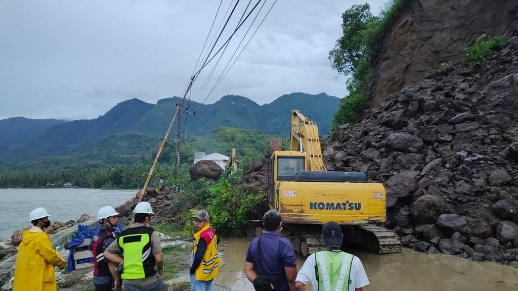 Kendaraan alat berat dikerahkan untuk mengangkut material longsoran di jalan poros Majene-Mamuju di Kecamatan Sendana, Majene, Selasa (11/10/2022). Hujan lebat menyebabkan longsor dan menbuat jalur Trans-Sulawesi ini lumpuh total.