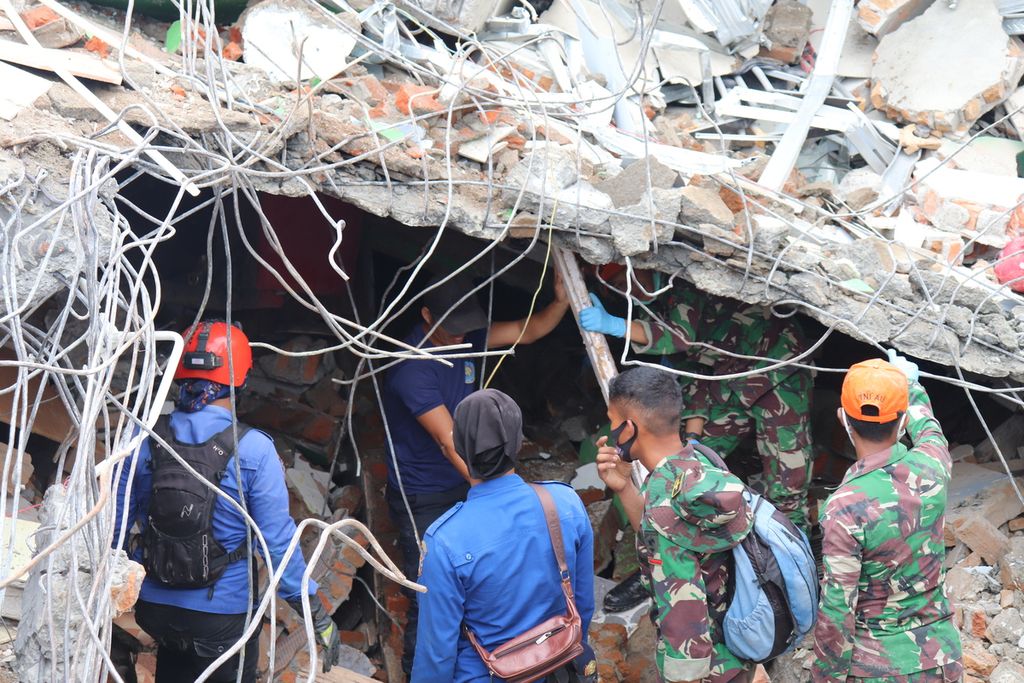 Tim pencarian dan penyelamatan memantau kondisi runtuhan bangunan akibat gempa untuk mengevakuasi dua korban di dalam runtuhan pada Sabtu (16/1/2021) di kawasan komersial di Kelurahan Mamuju, Kecamatan Mamuju, Kabupaten Mamuju, Sulawesi Barat.