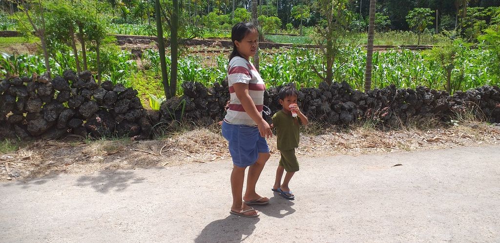 Agnes (34) salah satu ibu rumah tangga, warga Desa Oeltuah, Kabupaten Kupang, Sabtu (6/8/2022), dengan anaknya yang sedang mengonsumsi minuman ale-ale pemberian Agnes. Ibu-ibu desa cenderung memberi makanan dan minuman instan bagi anak-anak. Kondisi ini sering membuat anak-anak kurus, menderita gizi buruk, dan tengkes.