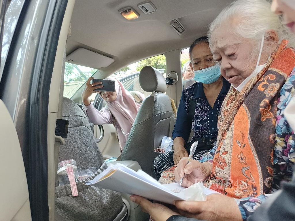 Seorang warga penerima ganti rugi lahan untuk proyek Kampung Seni Borobudur, menandatangani berkas-berkas ganti rugi di dalam mobil yang ditumpanginya, Rabu (10/1/2024). Warga tersebut akan melanjutkan perjalanan pulang ke rumah putrinya di Malang, Jawa Timur.