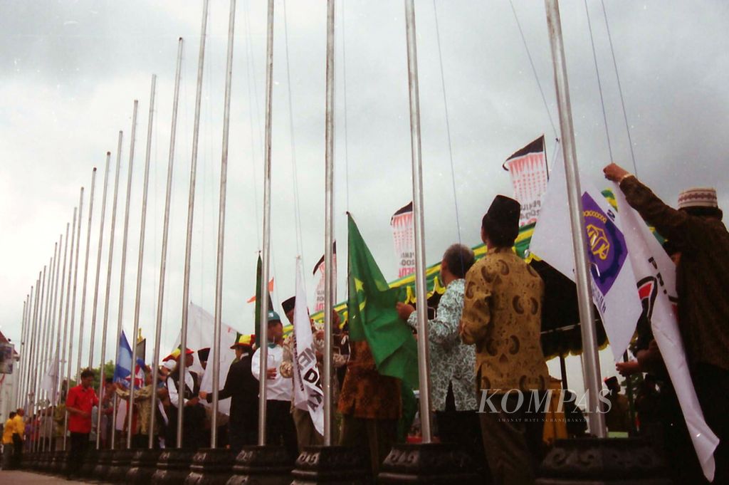 Pengurus 24 partai politik mengibarkan bendera parpol bersama-sama di tengah cuaca langit yang mendung di depan kantor Bank Indonesia Yogyakarta, Jumat (9/1/2004). Pengibaran bendera ini merupakan bagian dari sosialisasi parpol pada masa prakampanye yang ditetapkan selama sepuluh hari di Kota Yogyakarta, 9-19 Januari 2004. 