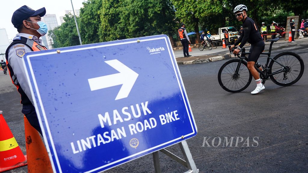 Pesepeda di sekitar rambu penunjuk arah jalur sepeda saat uji coba bagi sepeda di sekitar Jalan Layang Non-tol Kampung Melayu-Tanah Abang di titik Jalan KH Mas Mansyur, Jakarta, Minggu (13/6/2021). 
