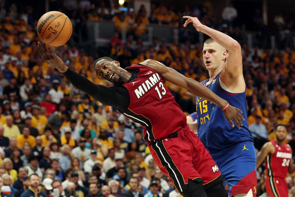 Pebasket Bam Adebayo dari Miami Heat (kiri) berebut bola dengan pebasket Nikola Jokic dari Denver Nuggets dalam laga pertama final NBA 2023 di Ball Arena, Denver, Amerika Serikat, Jumat (2/6/2023). Nuggets untuk pertama kali tampil di partai puncak sejak masuk liga pada 1977. 