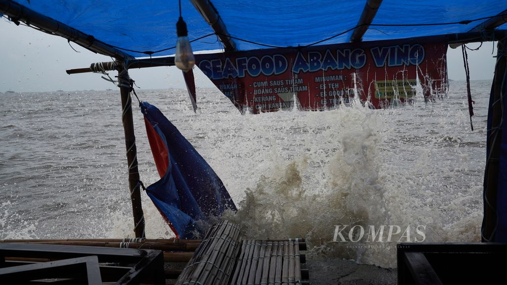 Ombak mengenai warung di Pantai Marunda, Cilincing, Jakarta Utara, Senin (26/12/2022). BMKG mengeluarkan prakiraan cuaca hingga tujuh hari ke depan masih akan ada gelombang sedang, tinggi hingga sangat tinggi di sejumlah perairan di tanah air. 