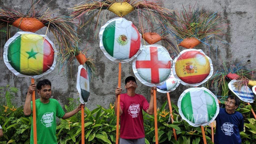 Warga membawa atribut bendera sejumlah negara peserta Piala Dunia Rusia di Pedukuhan Nayu, Kelurahan Nusukan, Kecamatan Banjarsari, Solo, Jawa Tengah, yang dideklarasikan sebagai Kampung Piala Dunia, Sabtu (21/4/2018) lalu.