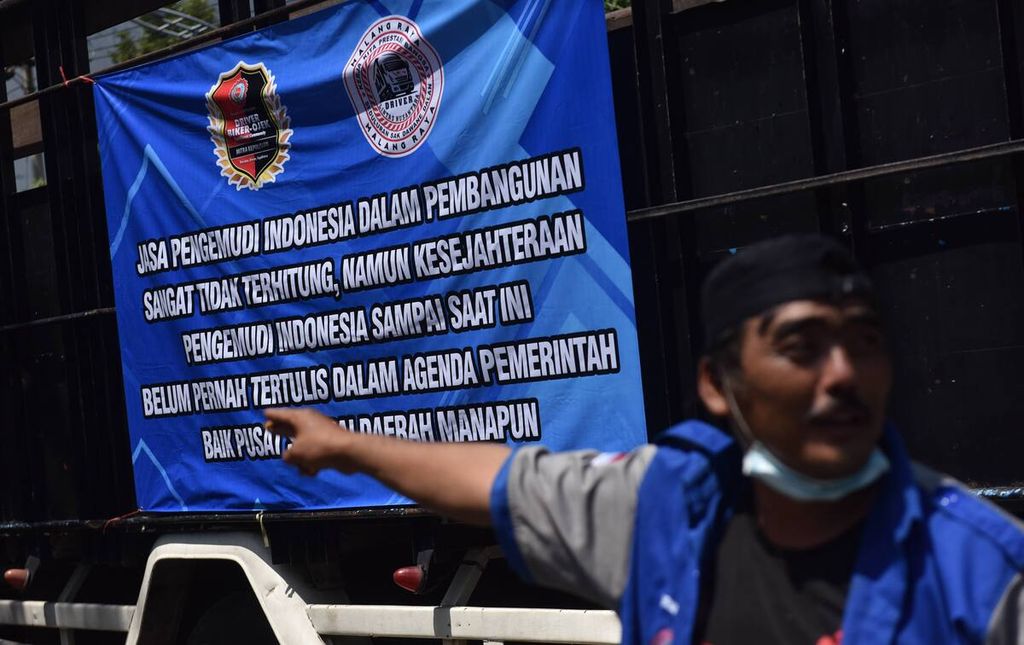 Spanduk dipasang di bak truk saat aksi unjuk rasa sopir truk di depan Kantor Dishub Jatim, Kota Surabaya, Jawa Timur, Selasa (22/2/2022). 
