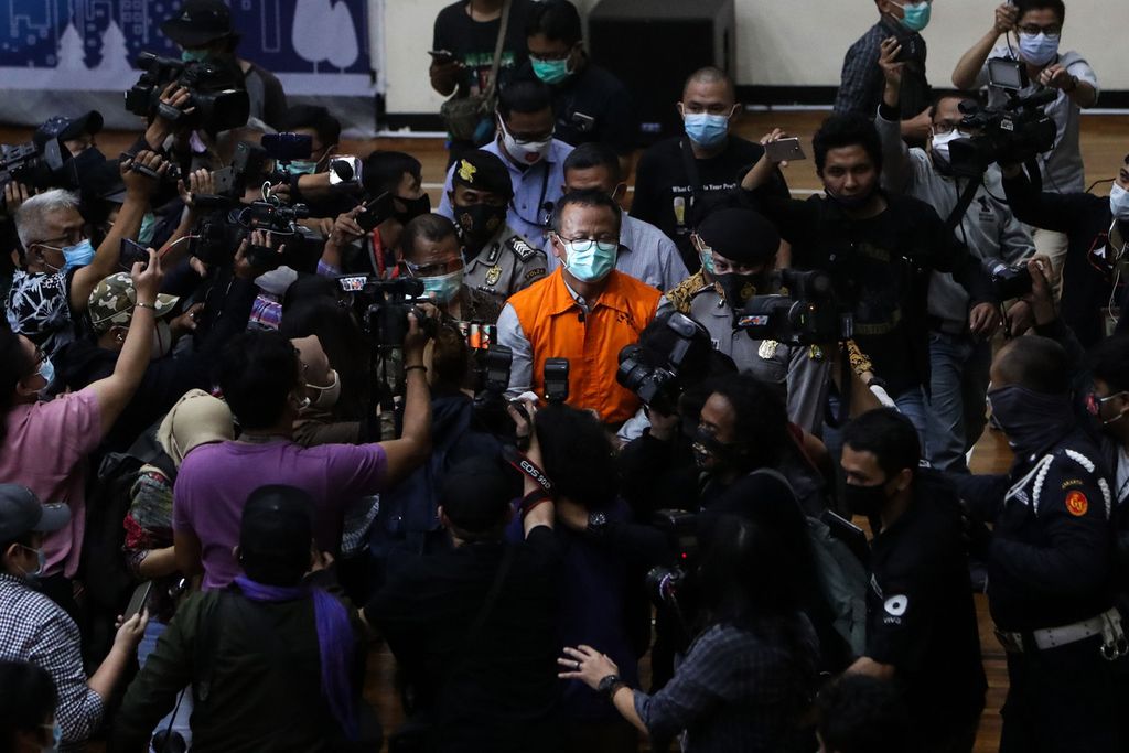 Menteri Perikanan dan Kelautan Edhy Prabowo (mengenakan rompi tahanan) dikerubuti wartawan saat meninggalkan tempat jumpa pers yang digelar Komisi Pemberantasan Korupsi terkait kasus kasus dugaan suap perizinan budidaya lobster tahun 2020 di Gedung KPK, Jakarta, Kamis (26/11/2020) dini hari.