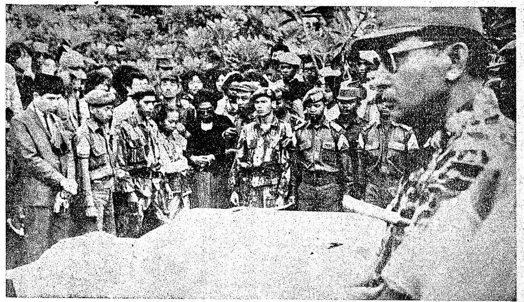 Nampak para djenazah pahlawan revolusi kita jang pada pagi 5 Oktober 1965 dikebumikan di Taman Pahlawan Kalibata Djakarta tengah diletakkan di atas liang makam, sedangkan para hadirin membatjakan doa bagi arwah mereka. Di sini ibu A Yani (pakaian hitam) memandang djenazah suaminja dengan rasa pedih. Djendral jang berseragam matjan loreng dan berkatjamata hitam adalah Majdjen Soeharto, Panglima Kostrad jang diserahi tugas memulihkan keamanan dan ketertiban.