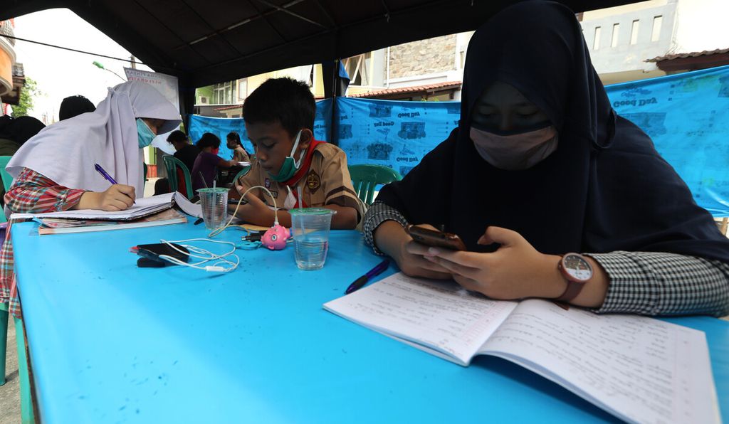 Pelajar dari berbagai jenjang sekolah mengerjakan tugas dengan pembelajaran jarak jauh (PJJ) dalam jaringan (daring) menggunakan fasilitas wifi gratis di tenda yang disediakan secara swadaya oleh warga RT 013/RW 02 Pondok Kelapa, Duren Sawit, Jakarta Timur, Rabu (12/8/2020). 