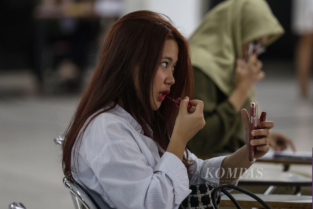 A job seeker applies make-up while looking for work at a job fair at Tama Jagakarsa University, South Jakarta, Tuesday (25/4/2024).