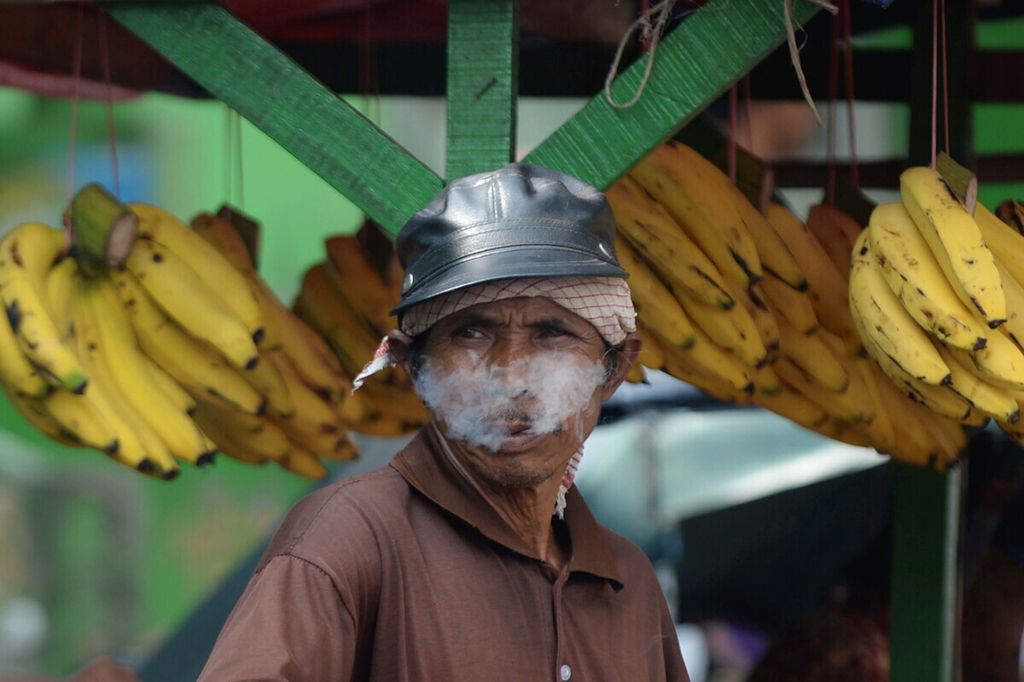 Pedagang buah kaki lima menikmati asap rokok saat menunggu pelanggan di Pasar Kranji, Bekasi Barat, Kota Bekasi, Jawa Barat, Senin (6/3/2017). Sejumlah penelitian menyebutkan bahwa perokok di Indonesia 70 persen di antaranya berasal dari kalangan keluarga miskin. 