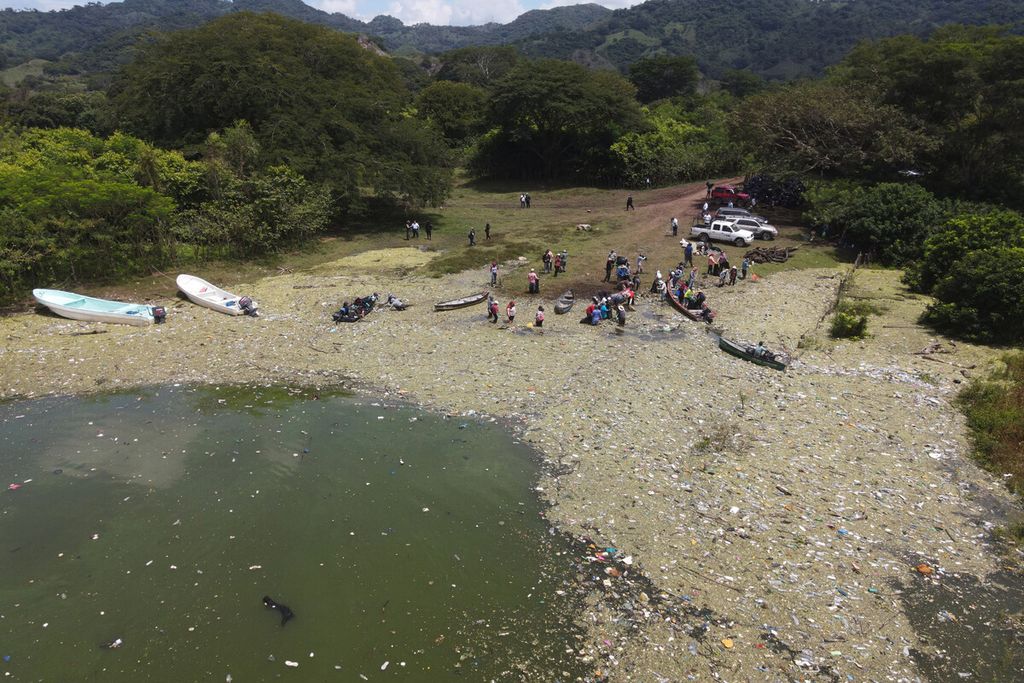 Orang-orang mengumpulkan limbah sampah plastik, kaca, dan bahan lainnya di Waduk Cerron Grande di Potonico, El Salvador, Jumat (9/9/2022). 