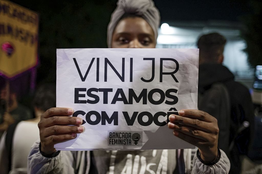 Seorang wanita membawa kertas bertuliskan "Vini Jr, kami bersamamu" dalam aksi protes menentang rasisme di luar Konsulat Brasil di Sao Paulo, Selasa (23/5/2023). Aksi tersebut untuk mendukung penyerang Real Madrid asal Brasil, Vinicius Junior, yang mendapat serangan rasial saat pertandingan Liga Spanyol. 