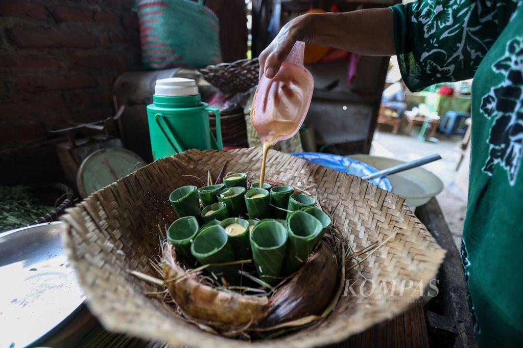 Tangan Raja Onah (53) menuangkan adonan kue apem ke dalam bungkus yang terbuat dari daun pisang di dapur rumahnya di Desa Kemiren, Kabupaten Banyuwangi, Jawa Timur, Sabtu (18/11/2023). 