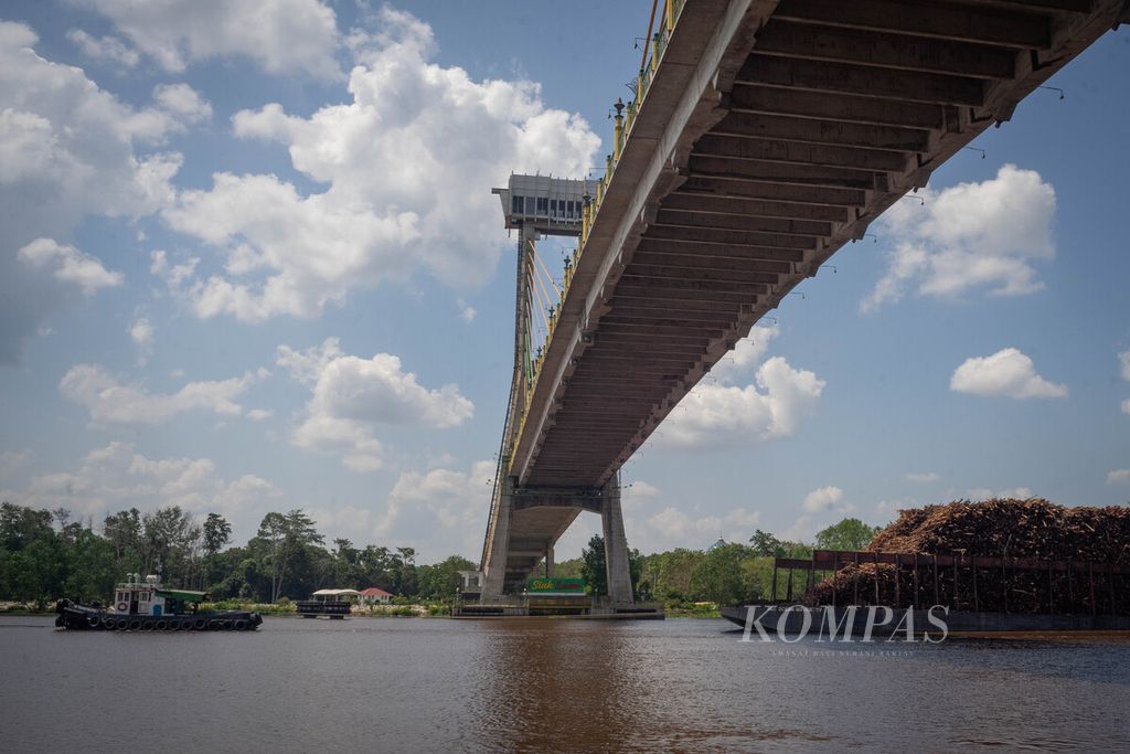 Tongkang pengangkut kayu untuk bahan baku kertas melintas di bawah Jembatan Tengku Agung Sultanah Latifah, Kabupaten Siak, Riau, Senin (7/8/2023). 