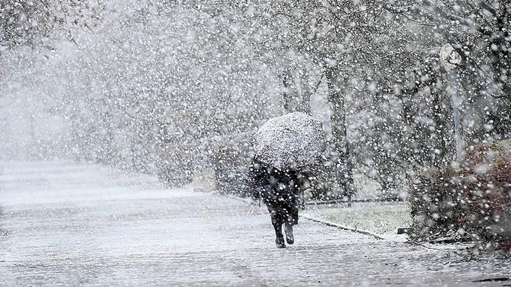 Seorang perempuan menggunakan payung untuk melindungi diri dari hujan salju lebat di Langenhagen, dekat Hanover, sebelah utara Jerman, 17 Januari 2018, saat suhu udara mendekati titik beku. 