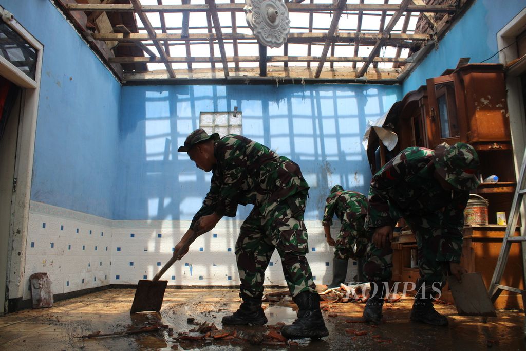 Petugas membersihkan rumah terdampak puting beliung di Desa Mangunarga, Kecamatan Cimanggung, Kabupaten Sumedang, Jawa Barat, Sabtu (24/2/2024). Sebagian besar bangunan rumah milik warga rusak di bagian atap sehingga belum bisa dihuni selama atapnya tidak diperbaiki.