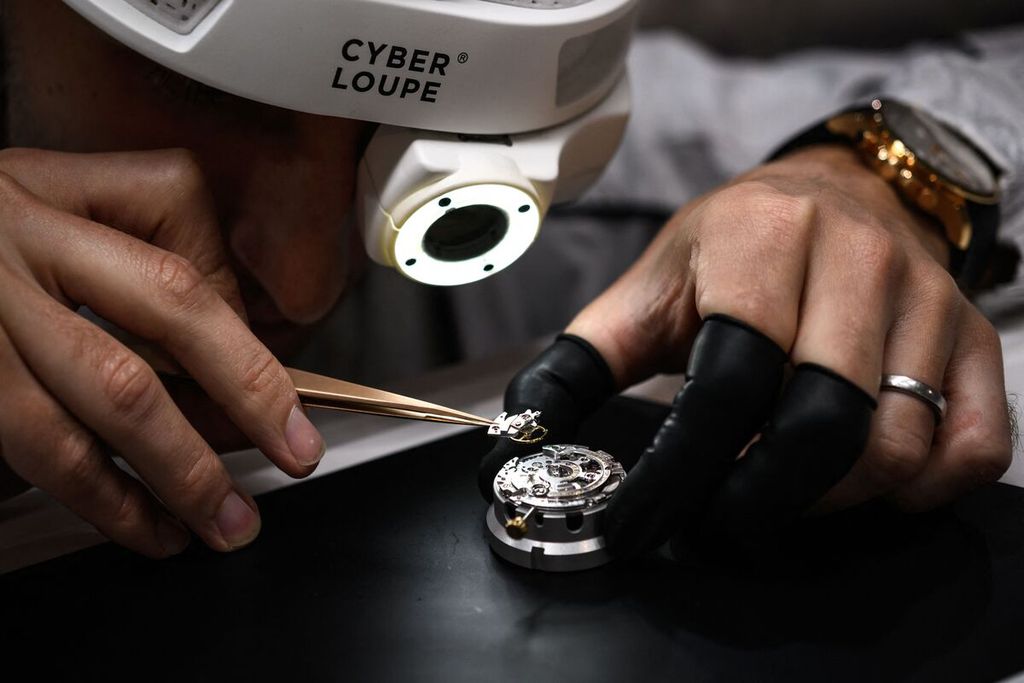 Seorang ahli pembuat jam tangan dengan menggunakan "cyberloupe" yaitu sebuah kaca pembesar digital tengah merakit sebuah jam tangan mewah karya produsen jam tangan asal Swiss, IWC pada hari pembukaan pameran Watches and Wonders Geneva di Geneva pada Rabu (30/3/2022).