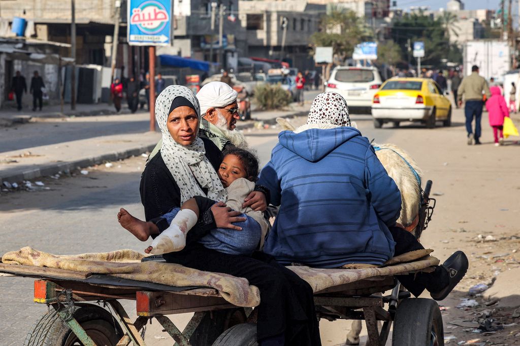 Seorang perempuan Palestina menggendong putrinya yang terluka saat mereka naik kereta yang ditarik keledai menuju klinik di Rafah di Jalur Gaza selatan pada 12 Februari 2024. 