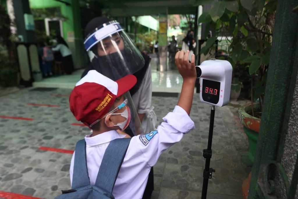 Siswa sekolah di Kota Malang masuk ke sekolah dan mengikuti protokol kesehatan yang diberlakukan.