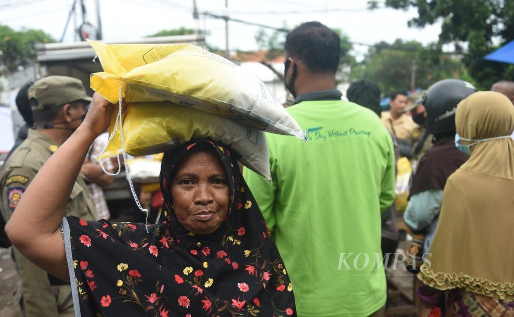 Warga membawa beras medium di atas kepalanya saat Operasi Pasar di Pasar Kembang, Surabaya, Minggu (5/2/2023).