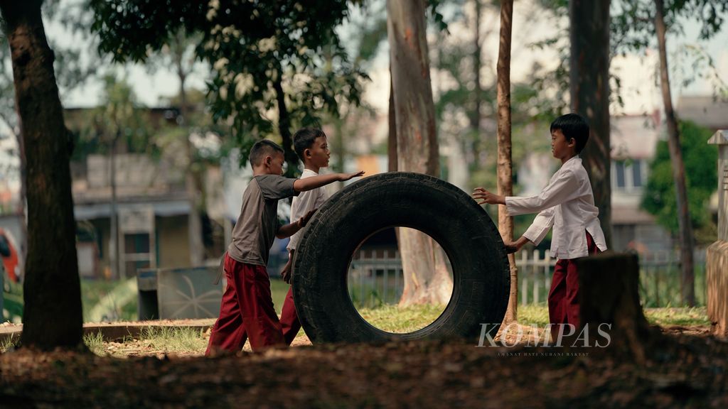 Pelajar sekolah dasar bermain ban truk sepulang sekolah di Kanal Timur, Duren Sawit, Jakarta Timur, Jumat (13/5/2022). Pembelajaran tatap muka 100 persen tiap hari terus didorong.