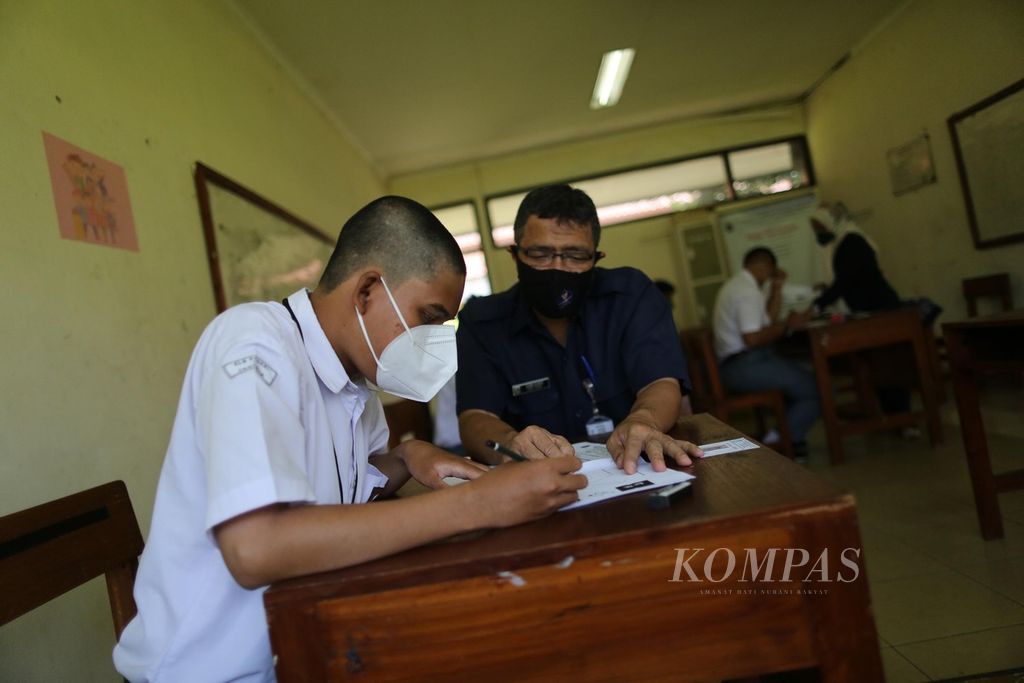 Guru pendamping membantu membacakan soal ujian saat siswa tunagrahita dari SMA SLB Negeri 1 Jakarta mengikuti ujian akhir sekolah, Senin (14/3/2022). Sebanyak 28 siswa SMA SLB Negeri 1 Jakarta mengikuti ujian akhir yang akan berlangsung selama lima hari.