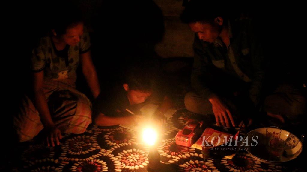 Suhaidi (7) ditemani ibu dan ayahnya belajar dengan menggunakan cahaya lampu teplok berbahan bakar minyak di rumahnya di Desa Tampur Paloh, Kecamatan Simpang Jernih, Kabupaten Aceh Timur, Aceh, Sabtu (16/9). Desa di pedalaman Aceh Timur itu hingga kini belum  mendapat aliran listrik.