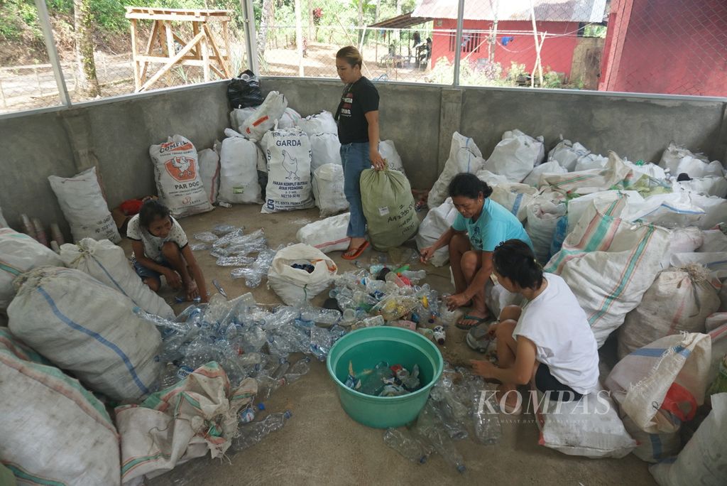 Beberapa pengurus dan nasabah Bank Sampah Induk Likupang menyortir sampah plastik di gudang bank sampah di Desa Serawet, Likupang Timur, Minahasa Utara, Senin (13/6/2022).