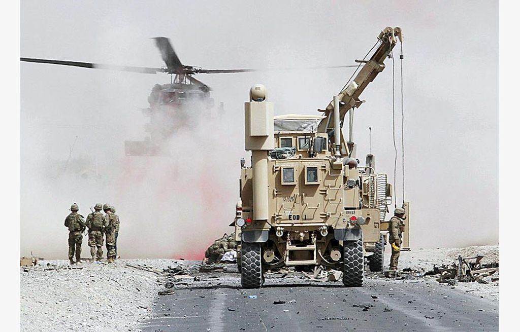 Tentara AS memeriksa kerusakan pada sebuah kendaraan lapis baja koalisi militer yang dipimpin Pakta Pertahanan Atlantik Utara (NATO) setelah serangan bunuh diri di Provinsi Kandahar, Afganistan, Rabu (2/8). 
