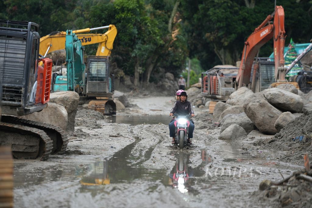 Warga melewati jalan berlumpur akibat banjir bandang di Desa Simangulampe, Kecamatan Baktiraja, Kabupaten Humbang Hasundutan, Sumatera Utara, Kamis (7/12/2023). 