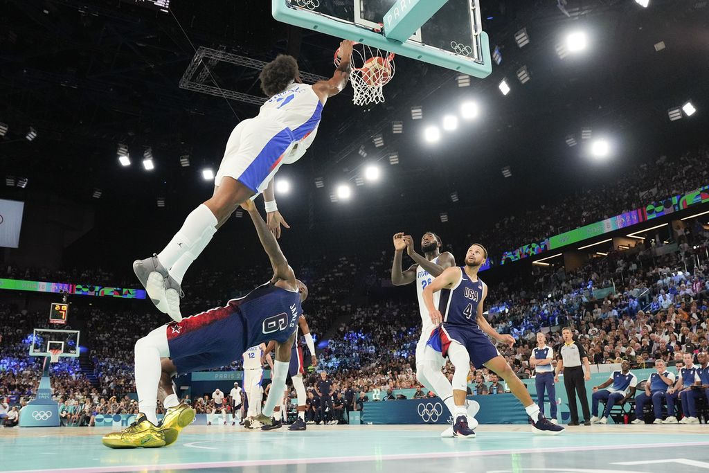 Pemain Perancis, Guerschon Yabusele, melompati pemain AS, LeBron James, untuk melakukan <i>dunk </i>pada final basket Olimpiade Paris 2024 di Bercy Arena, Paris, 10 Agustus 2024. AS memenangi laga final untuk merebut medali emas Olimpiade.