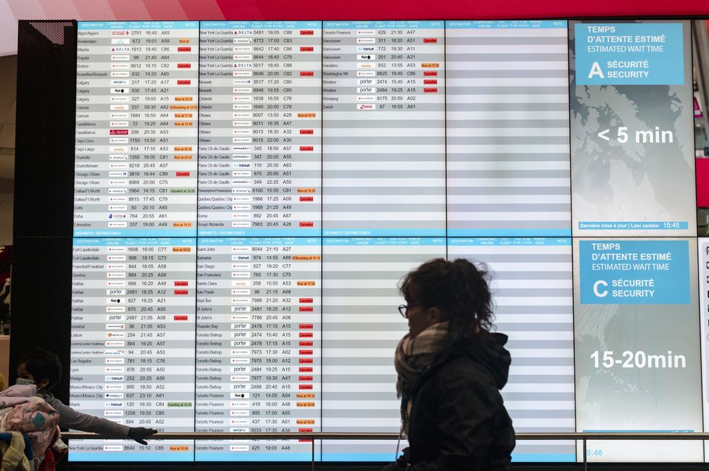 Penumpang tengah mengecek jadwal penerbangan di bandara internasional Pierre-Elliot Trudeau, Montreal, Quebec, Kanada pada Jumat (23/12/2022).