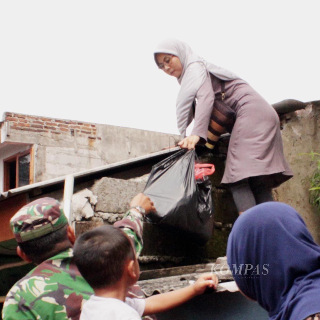 Seorang ibu  memanjat atap untuk mencapai rumah yang terendam banjir demi mengambil selimut bagi anaknya yang mengungsi di GOR Total Persada, Kota Tangerang, Banten, Senin (8/5). Warga mengungsi sejak Minggu sore setelah Kali Ledug meluap.