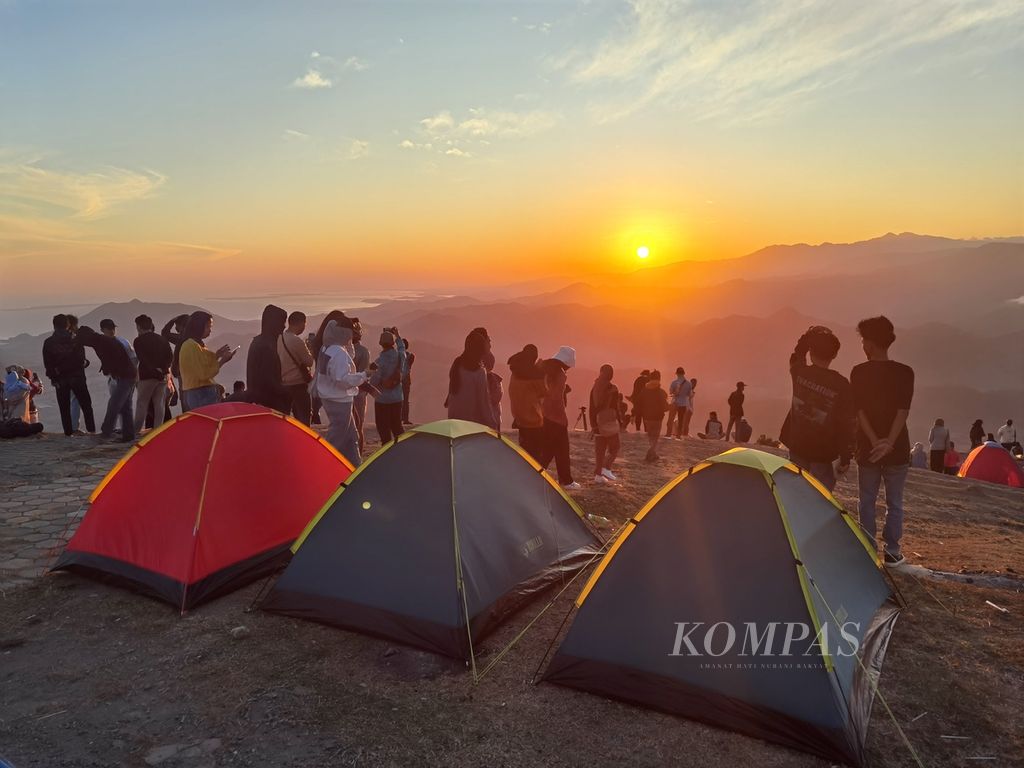 Pengunjung yang berasal dari berbagai daerah seperti Sumbawa, Lombok, bahkan pulau Jawa, menikmati suasana matahari terbit dari atas Bukit Mantar di Desa Mantar, Kecamatan Poto Tano, Kabupaten Sumbawa Barat, Nusa Tenggara Barat, Minggu (16/7/2023). 