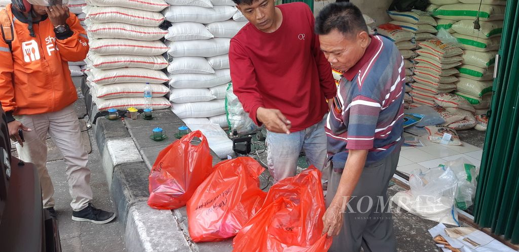 Mari (kanan), pedagang beras di Pasar Induk Cipinang, Jakarta Timur, mengecek beras kemasan sebelum diantar kepada pembeli daring pada Selasa (13/2/2024) siang.