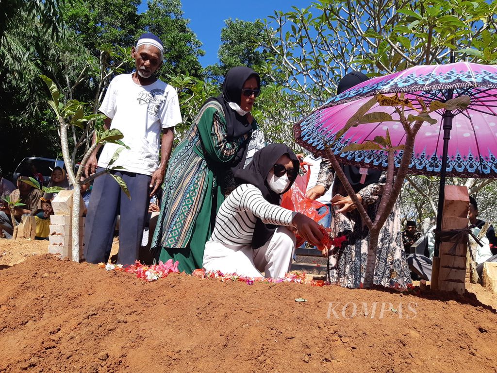 Alda Cahya (17), anak korban Irsad dan Wahyu Tri, ditemani keluarganya menabur bunga dan berdoa di pemakaman di Desa Tanjung Rejo, Kecamatan Negeri Katon, Kabupaten Pesawaran, Lampung, Sabtu (8/4/2023).