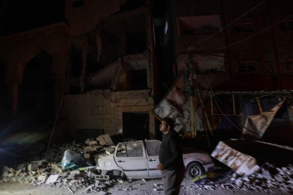 Seorang warga berjalan melewati bangunan yang hancur di Rafah, selatan Gaza, Senin (12/2/2024), akibat serangan Israel di wilayah itu. 