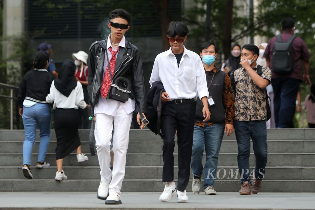 Ale (19) (dasi merah), pencetus Citayam Fashion Week berjalan di Taman Stasiun MRT Dukuh Atas, Jakarta, Jumat (8/7/2022). 