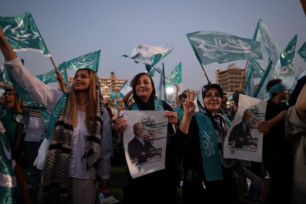 Para perempuan membawa poster bergambar kandidat presiden dari kubu reformis, Masoud Pezeshkian, dalam sebuah kampanye di salah satu stadion di Teheran, Iran, 3 Juli 2024. 