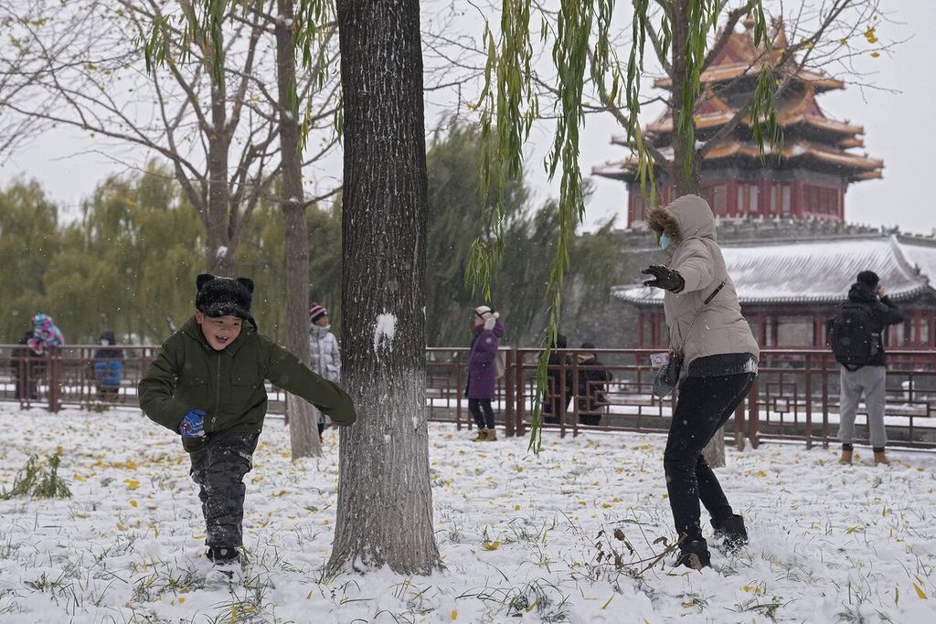 Children and their family members play in the snow near the Forbidden City, Beijing, China, Sunday (7/11/2021).