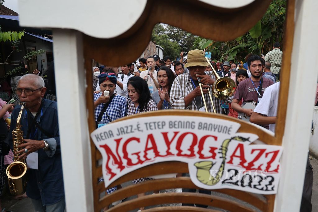 Kelompok Huaton Dixie tampil dengan berkeliling dusun dalam ajang Ngayogjazz di Dusun Cibuk Kidul, Margoluwih, Seyegan, Sleman, DI Yogyakarta, Sabtu (19/11/2022). Ngayogjazz kembali digelar dengan menghadirkan 40 penampil.