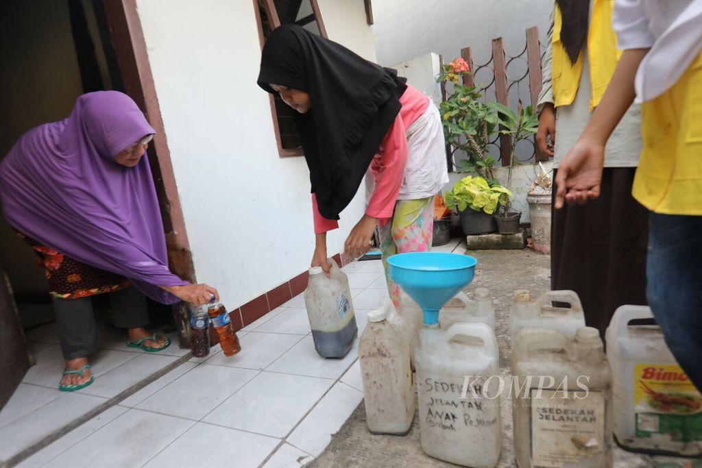 Warga memberikan minyak jelantah yang dikumpulkan ek dalam botol plastik kepada anak-anak anggota Komunitas Pejuang Subuh yang menjemput dari rumah ke rumah para donatur di kawasan Jatinegara, Cakung, Jakarta Timur, Jumat (28/10/2022). 