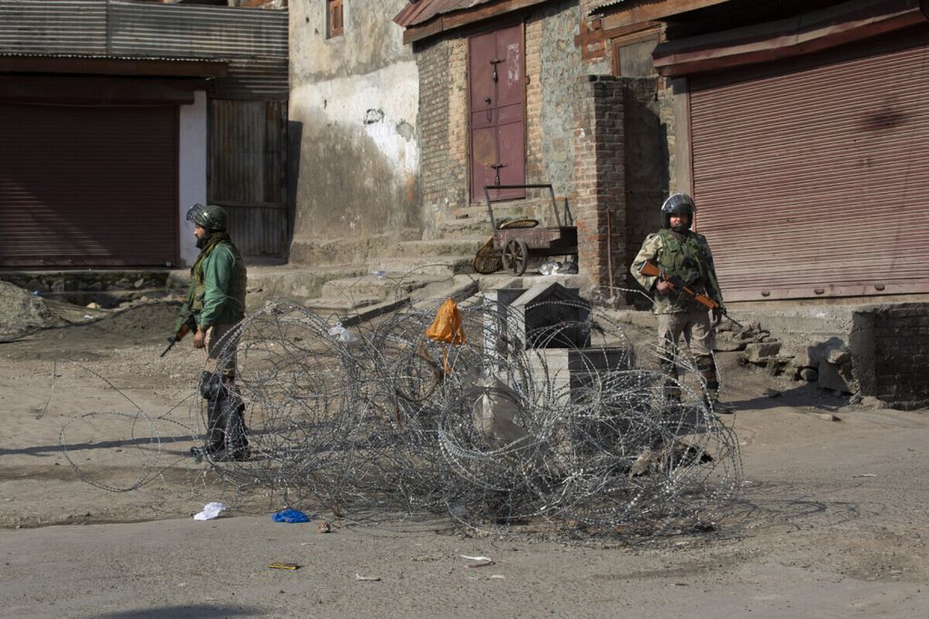 Tentara paramiliter India berjaga di dekat kawat berduri yang dipasang sebagai blokade jalan saat terjadi pemogokan di Srinagar, Kashmir, India, Minggu (9/2/2020). 