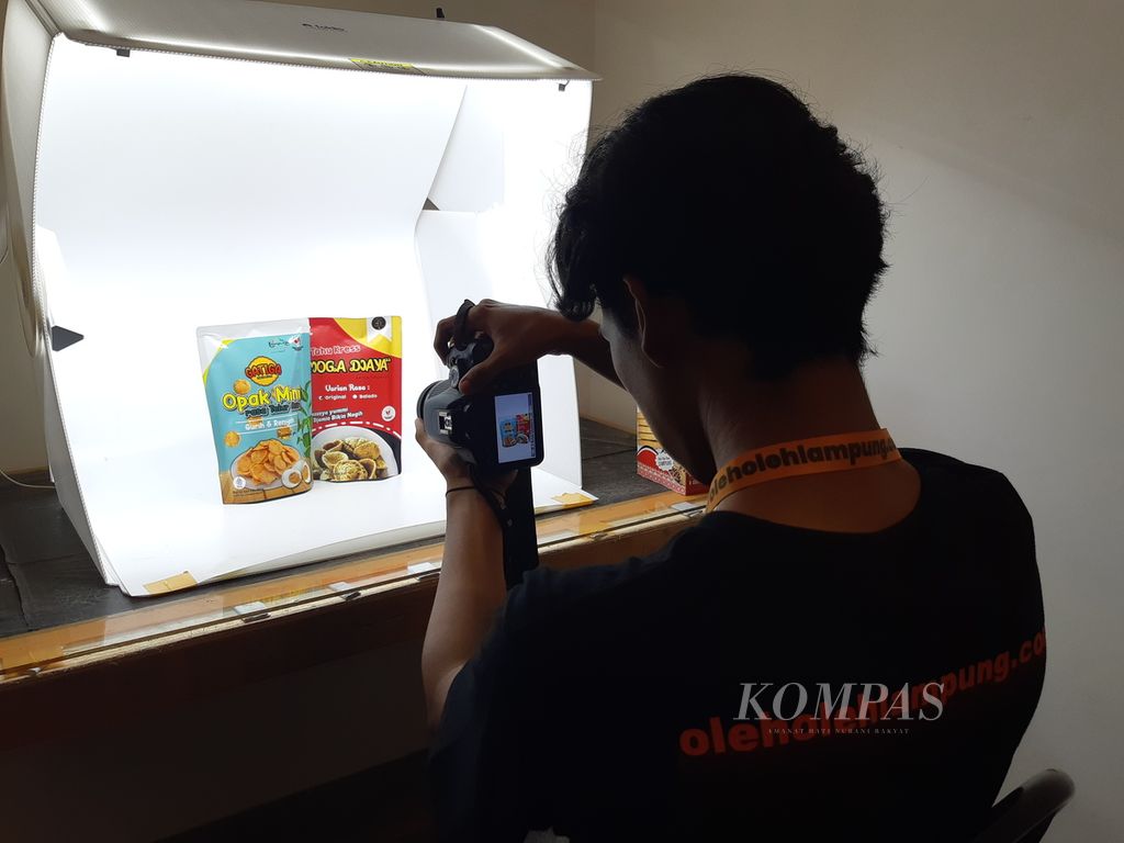 Seorang mahasiswa membantu memfoto produk opak dan tahu kemasan di galeri oleholehlampung.com pada Kamis (15/6/2023).