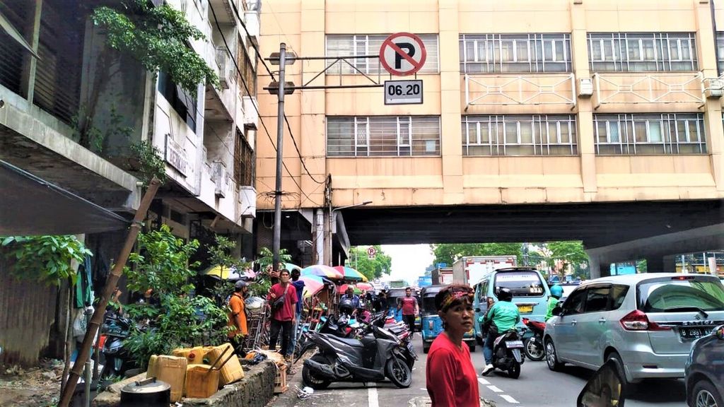 Yeni Kartika (45), juru parkir yang sedang menunggu para pemarkir yang hendak parkir di pinggir jalan, Rabu (5/10/2022). Lebih dari 10 sepeda motor terparkir di bawah rambu dilarang parkir di Pasar Tanah Abang Blok A, Jakarta Pusat.