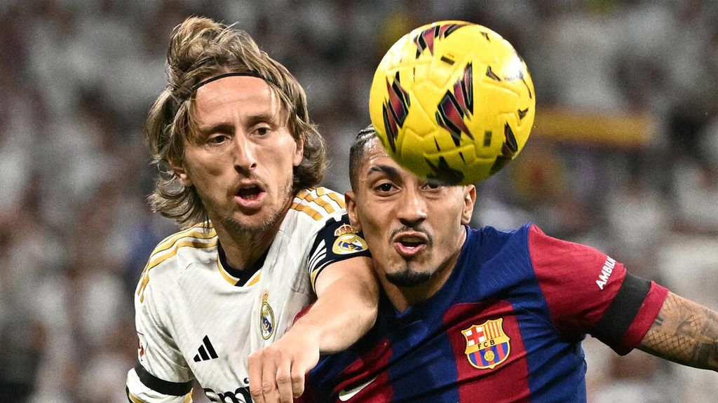 Penyerang Barcelona, Raphinha (kanan), berebut bola dengan gelandang Real Madrid, Luka Modric, pada pertandingan sepak bola Liga Spanyol di Stadion Santiago Bernabeu, Madrid, Senin (22/4/2024) dini hari WIB. Dalam laga yang berlangsung sengit ini, Real Madrid menang 3-2. 