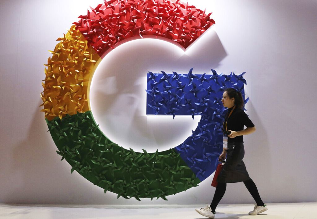Foto bertanggal 5 November 2018 ini memperlihatkan seorang perempuan berjalan melewati logo Google pada ajang China International Import Expo di Shanghai, China. 